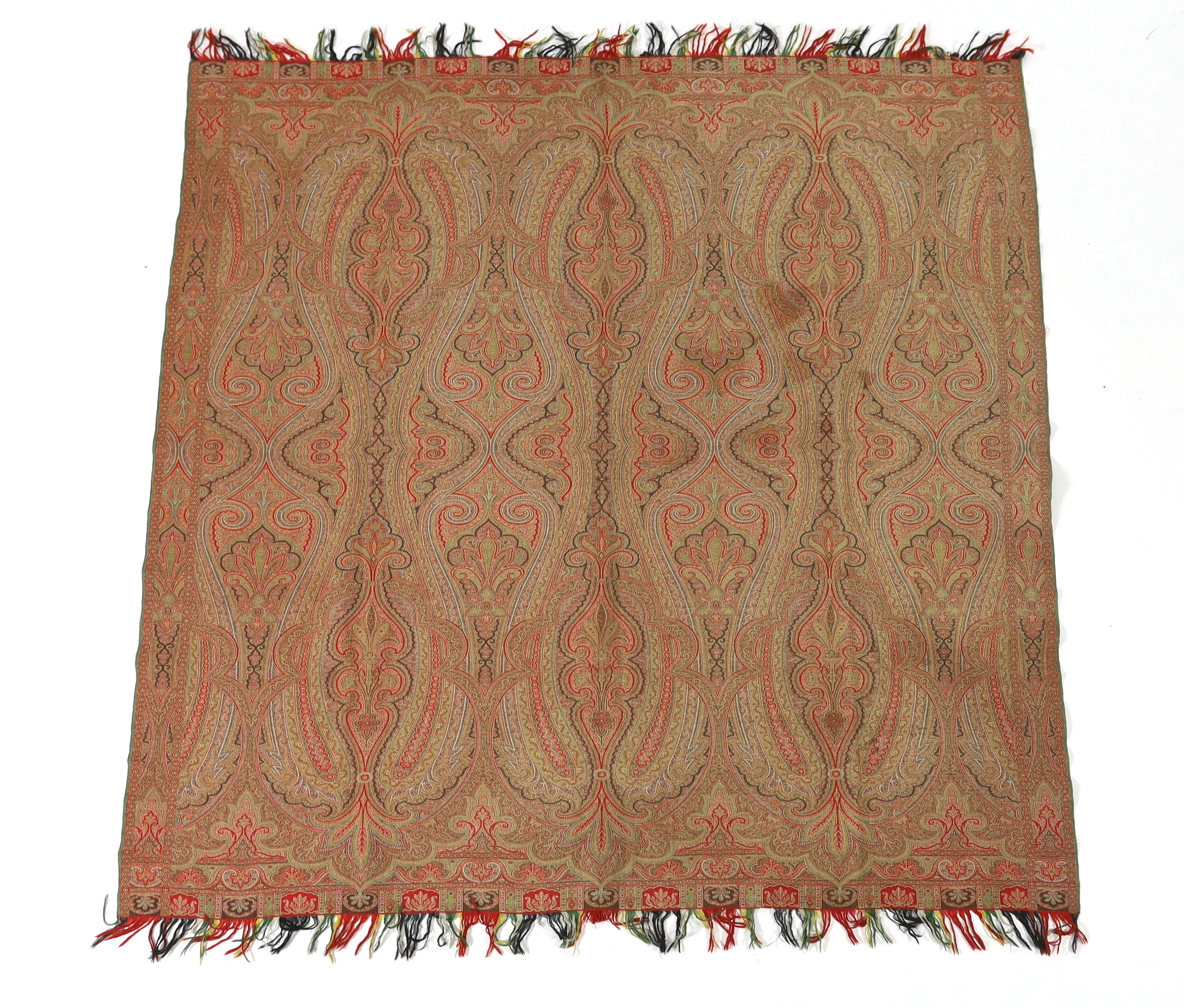 An 1860’s, reversible woven wool Paisley shawl, woven with green, red, ochre and brown, with a woven border and fringing both ends. 166cm wide x 169cm long